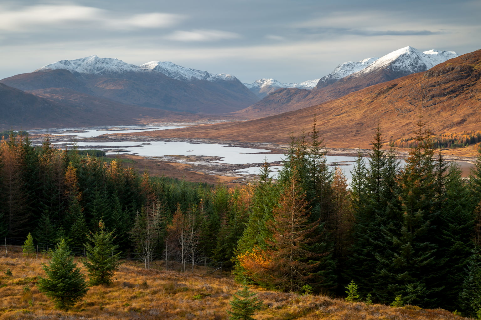 Lock Loyne in Scotland on an autumn day with snow capped mountains in the background.