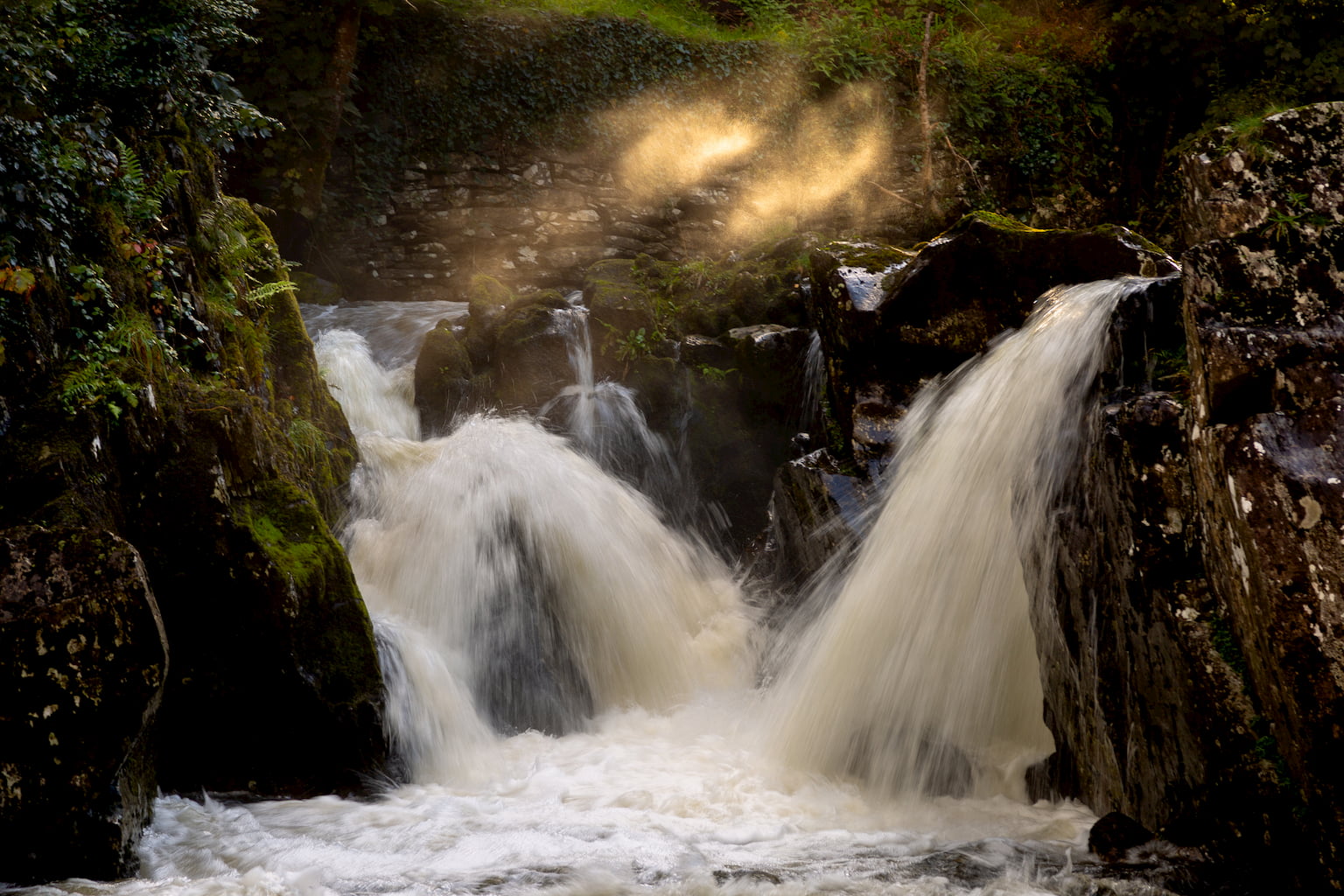 Initmate photograph of waterfall on the River Conwy at Betws-y-Coed with sunlight streaming through.
